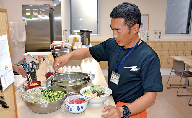 野菜と肉みそを麺に盛りつける小赤澤主査